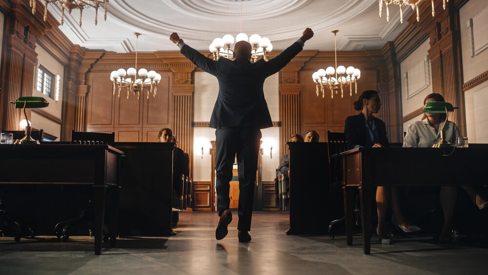 A man walking out of a court room with his hands in the air celebrating a victory 