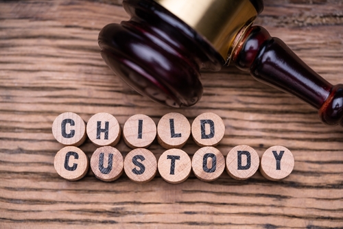 A gavel rests beside wooden tiles spelling "CHILD CUSTODY" on a wooden surface, reflecting the complexities of custody in Texas divorce proceedings.