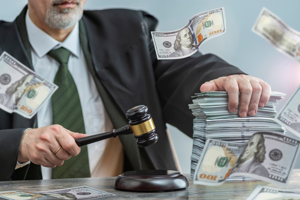 Judge and money concept. Judge's gavel on the table. Law Lord wearing gown using a hammer for verdict, justice judgment at courts of law. Dollars, bill, corruption, cost, finances, expenses, salary.