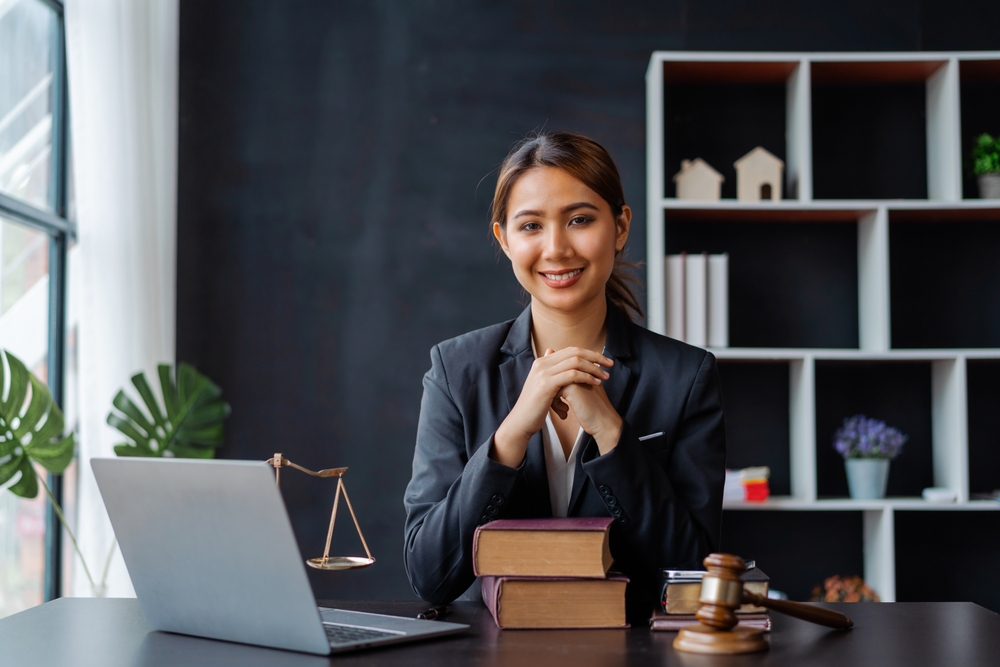 Looking camera. Young Attractive Asian female lawyer working in office with contract and law books when sitting at desk. Law, legal services, advice, Justice and real estate concept.