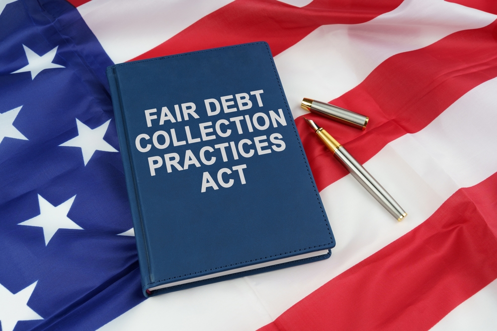 Law concept. On the US flag lies a pen and a book with the inscription - FAIR DEBT COLLECTION PRACTICES ACT