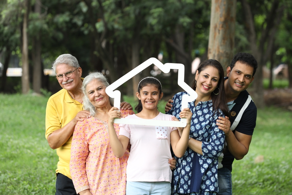 Indian happy family holding Papercut Family House. Concept -  Asian Family bonding Real Estate in india.