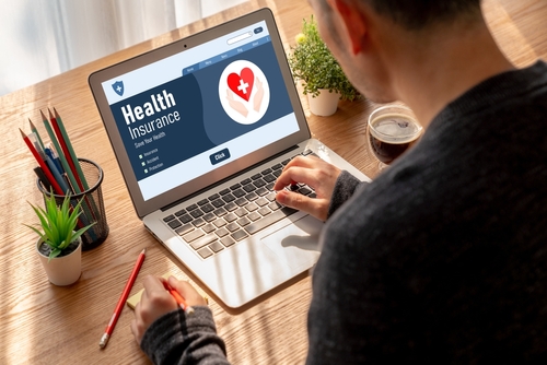 a man typing in laptop with health insurance is written 