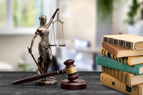 A statue of Lady Justice, a gavel, and a stack of books sit elegantly on a table against a blurred office backdrop, symbolizing the pathway through legal matters like navigating divorce in Texas without going to court.