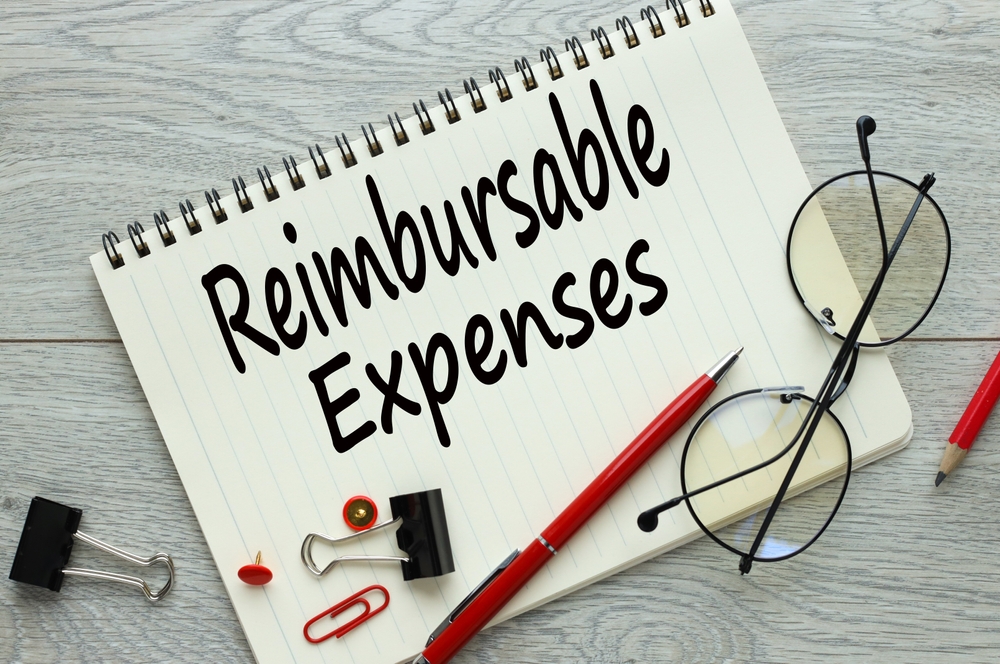 reimbursable expenses. light wooden background. text on a notepad. red pencil and paper clips