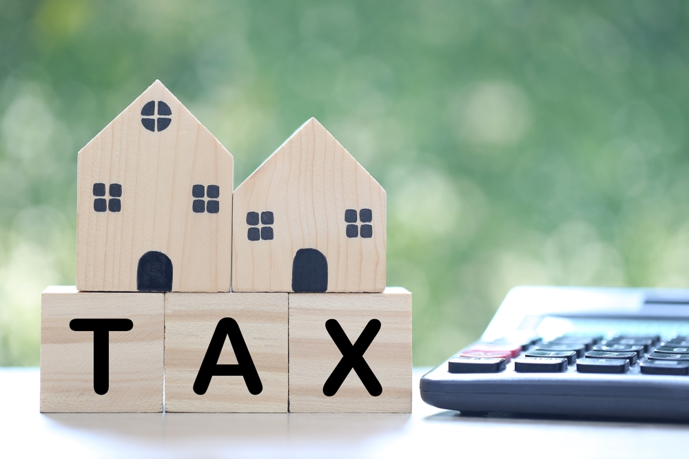 Estate tax,Model house and tax wooden text with calculator on green background, Business investment and Property tax concept 