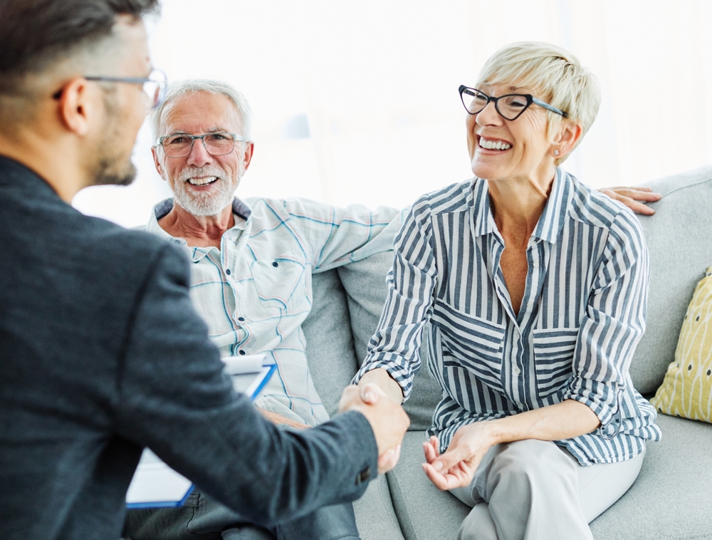 Happy senior old family couple clients make financial insurance estate business deal handshake agent lawyer, satisfied mature customers shake hand meeting bank manager agree on investment contract