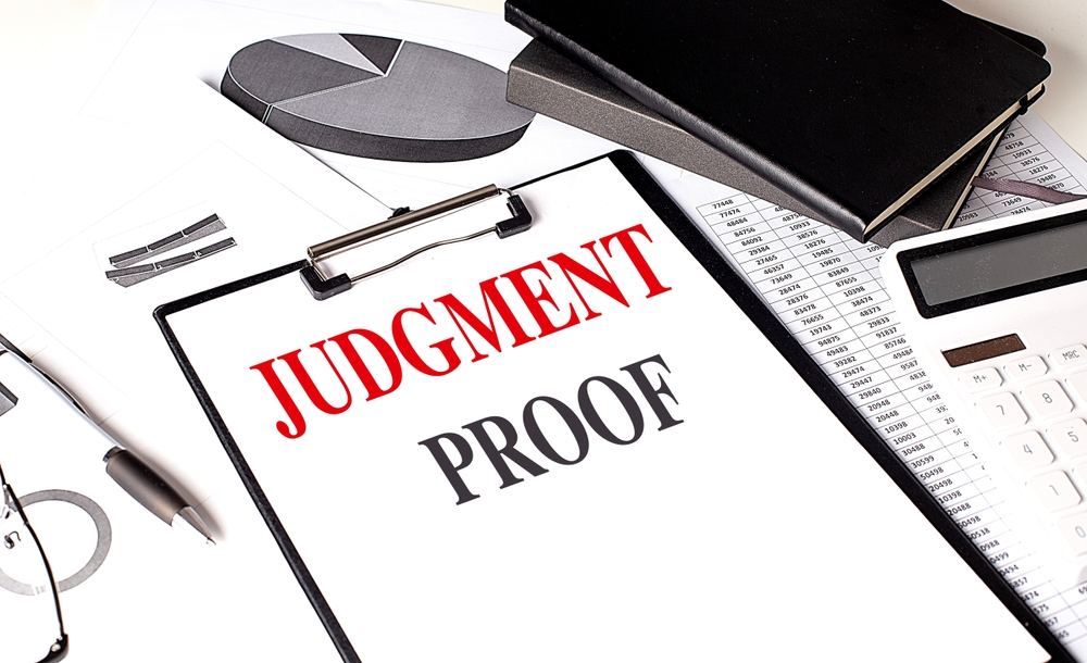 JUDGMENT PROOF text on a clipboard on chart with notebook and calculator