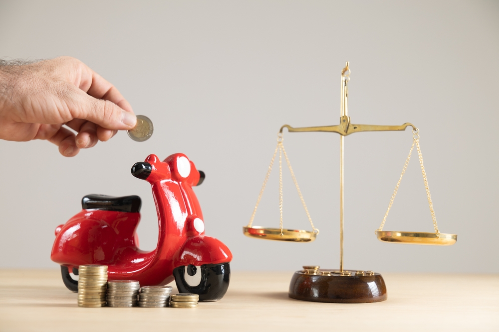 Close-up yellow motorbike piggy bank with scales and money, free background, copyspace, car insurance savings, vehicle insurer, vehicle accident