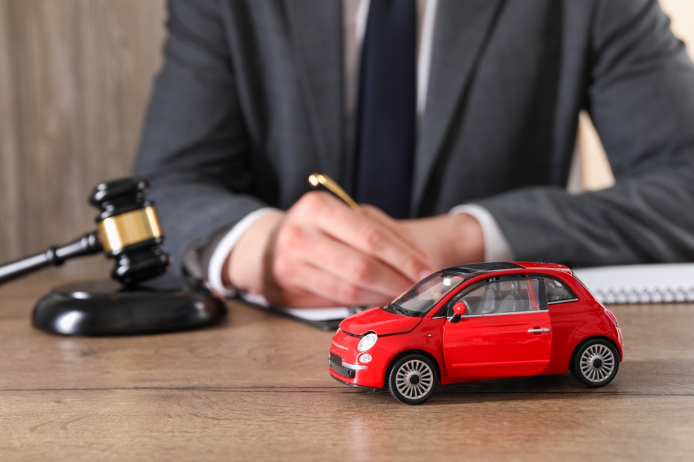Auto accident law. Man working at wooden table indoors, focus on toy car