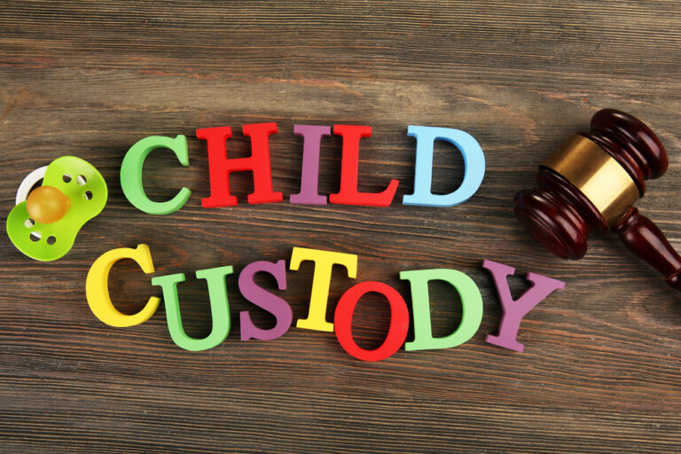 A gavel, a dummy and colourful letters regarding child-custody and family-law concept
