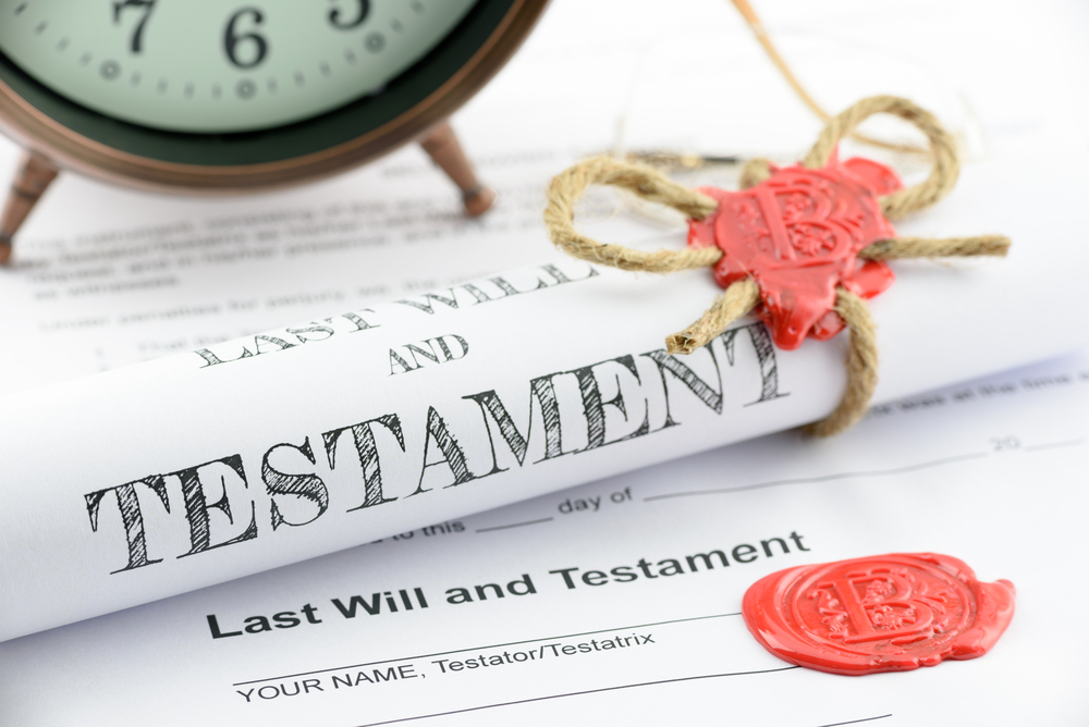 Rolled up scroll of last will and testament fastened with natural brown jute twine hemp rope, sealed with sealing wax and stamped with alphabet letter B. Decorated with an antique clock on a table.