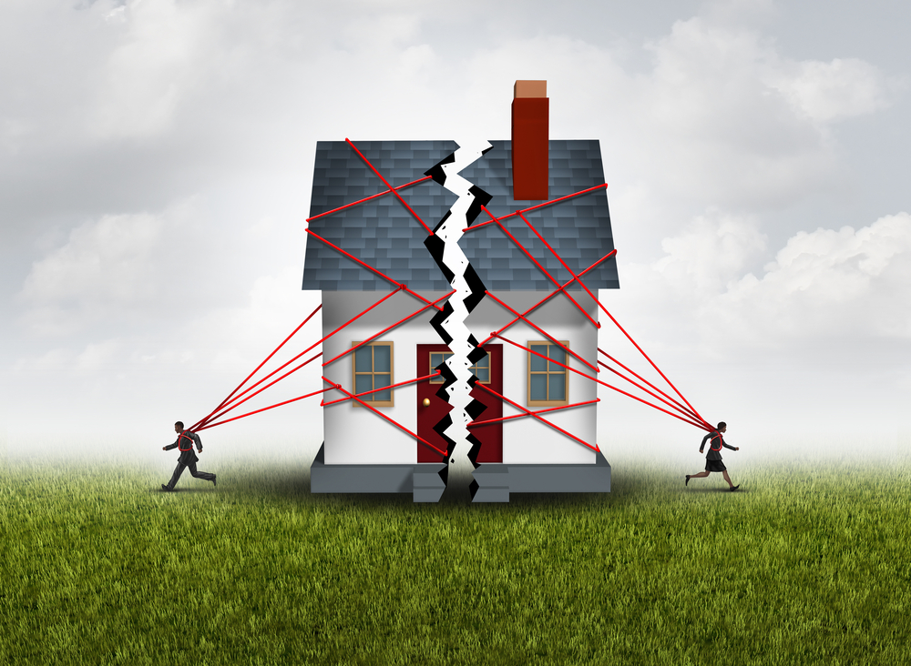 Broken family after a bitter divorce settlement and separation with a couple in a bad relationship breaking a house apart showing the concept of a marriage dispute with 3D illustration elements.
