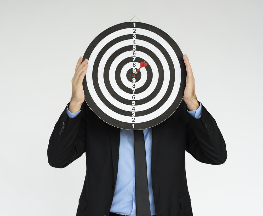 A businessman holding a target in front of his face 