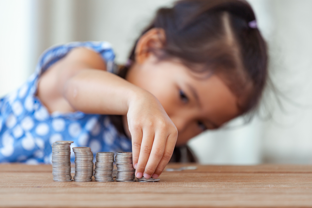 Cute asian little girl playing with coins making stacks of money,kid saving money for the future concept