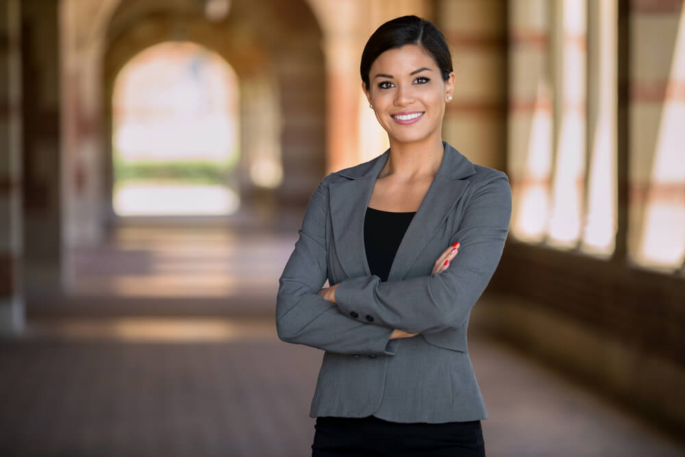 Women in a suit standing with her arms crossed and a smile on her face