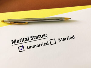 A paper on top of a yellow folder, the paper says marital status with two options, the first option has a check mark next to it and says unmarried and the second option says married