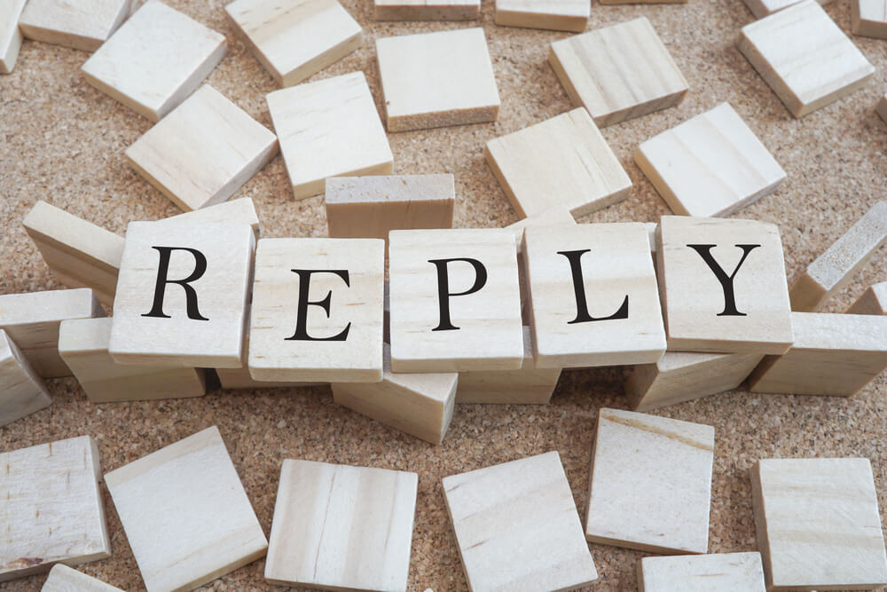 Wooden blocks scattered on a table and the word reply is spelled out in five wooden blocks