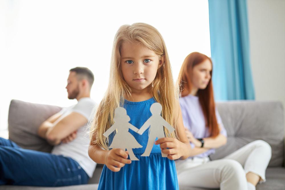 A girl holding paper people in the background, therapy divorce.