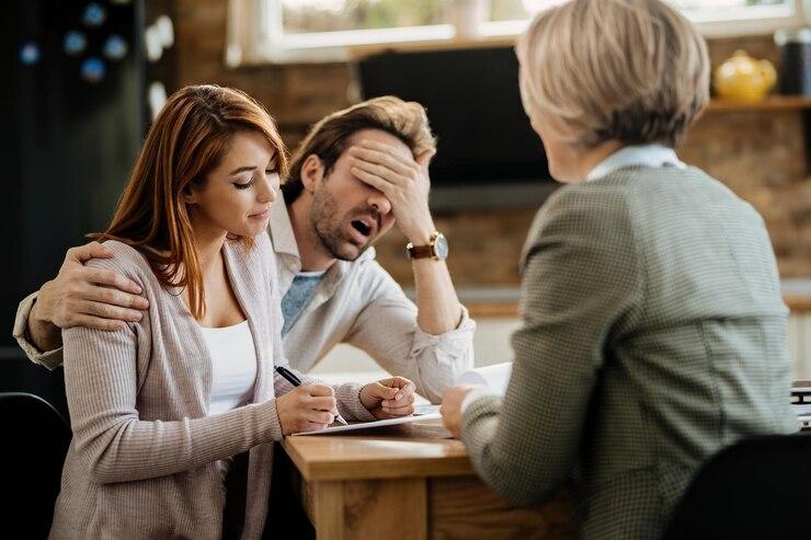 A couple appears stressed while signing their divorce documents in front of an official.