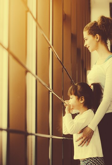 A woman and a young child, standing by a railing, looking out contemplatively.