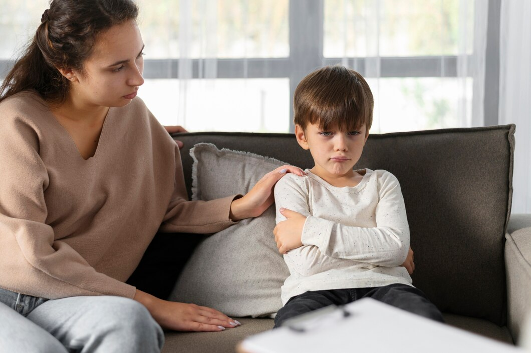 A woman comforting a young boy who appears upset, sitting on a sofa