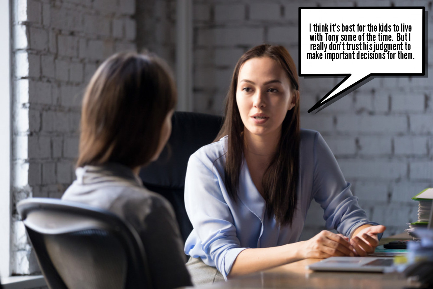 Two professional women engaged in a serious conversation across a table in an office setting.