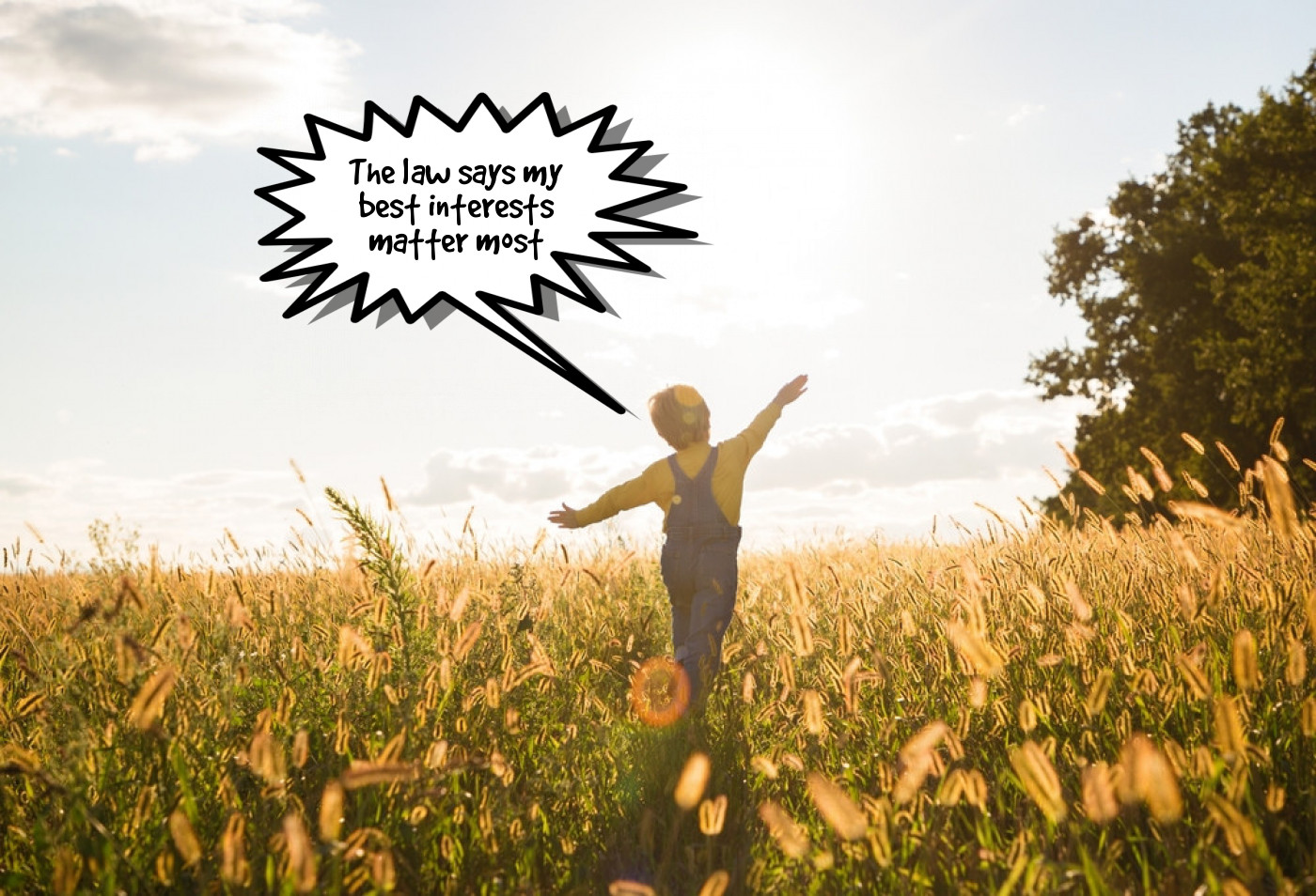 Child with arms outstretched standing in a sunny field 