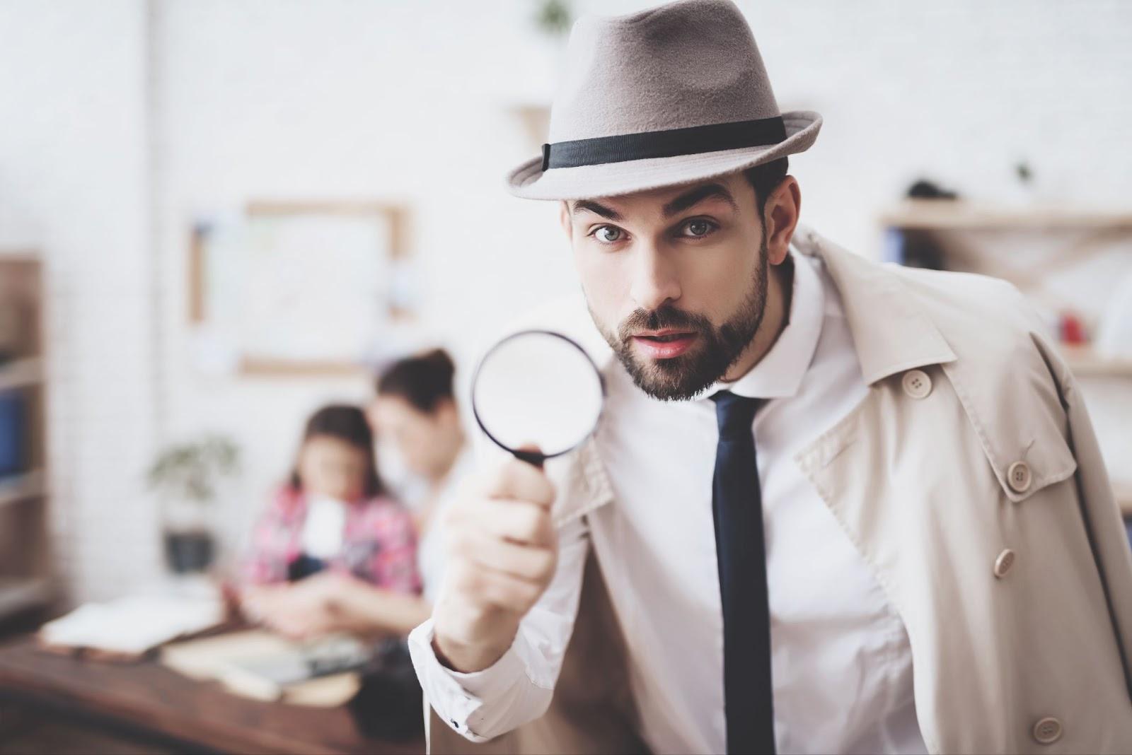 Man in a detective costume,holding a magnifying glass.
