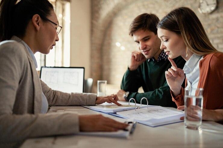 Three professionals discussing documents at a meeting table.