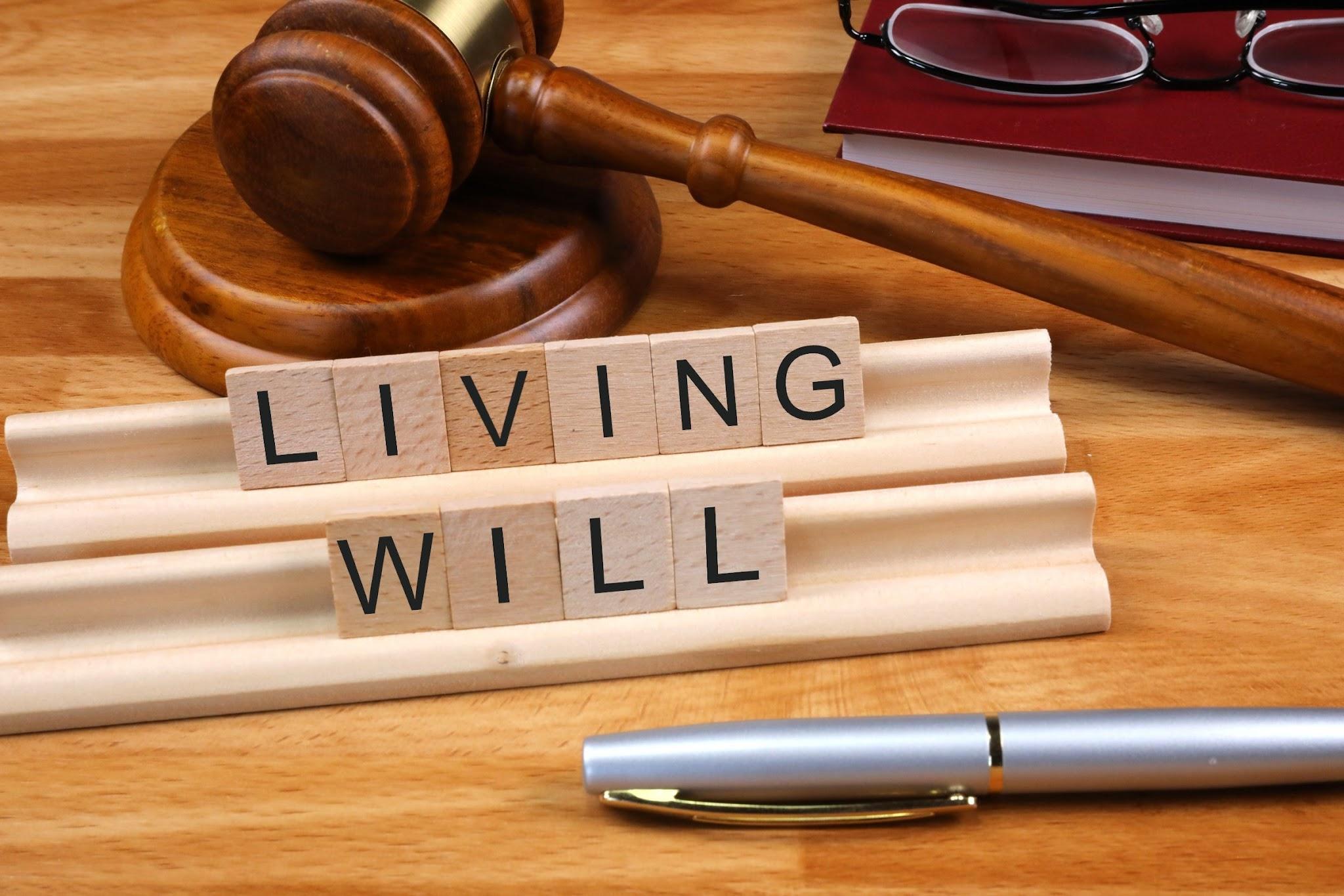 Wooden gavel and scrabble tiles spelling "What is a living will in Texas" on a desk with rolled documents, a pen, and glasses.