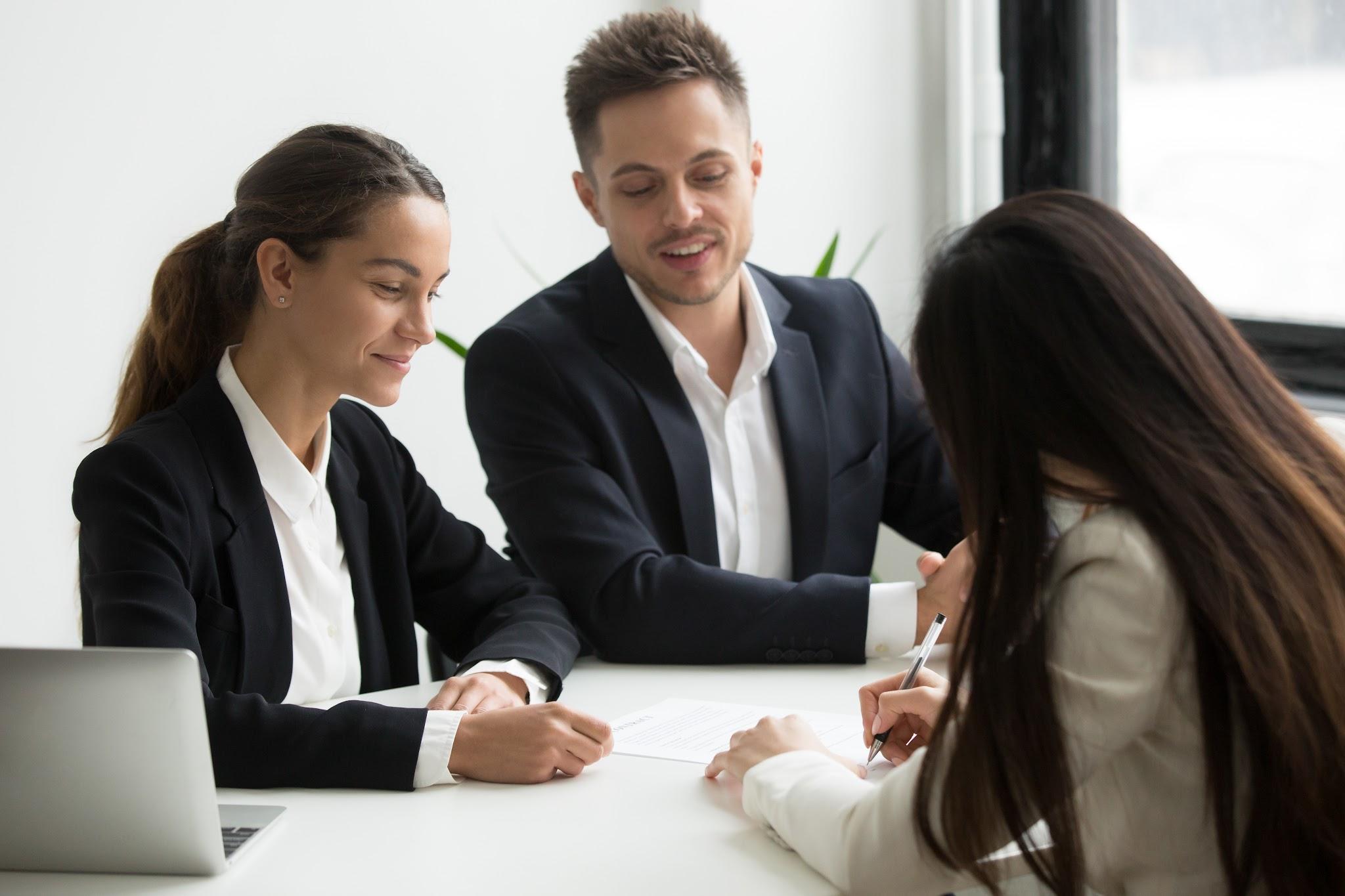 Three business professionals, two women and one man, engage in a discussion at a table with a laptop about what is a living will in Texas.