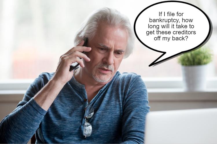 Older man with gray hair and beard, wearing glasses and a blue shirt, talking on the phone with a speech bubble that reads, "If I file for bankruptcy, how long will it take to get these creditors off my back?.