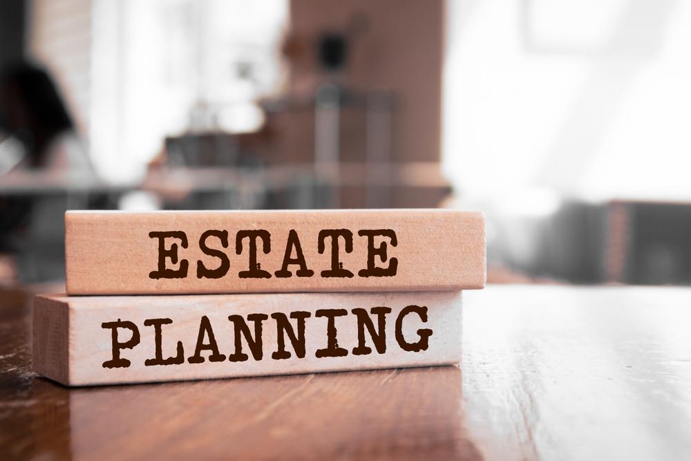 Two wooden blocks stacked on a table with the words "Estate Planning" in bold letters.