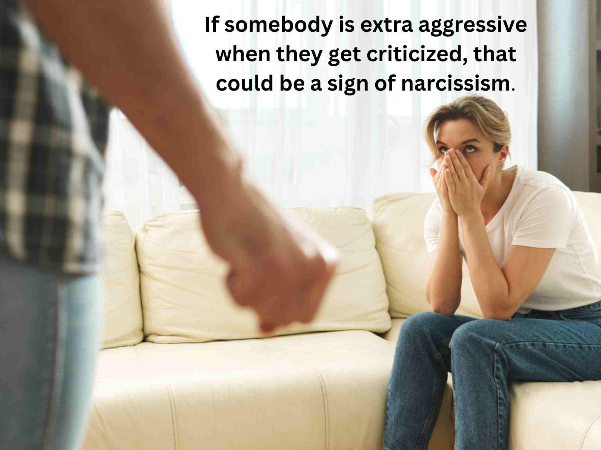 Person sitting on a couch looking upset, hands near their face, while someone stands with a clenched fist. Text reads: "If somebody is extra aggressive when they get criticized, that could be a sign of narcissist
