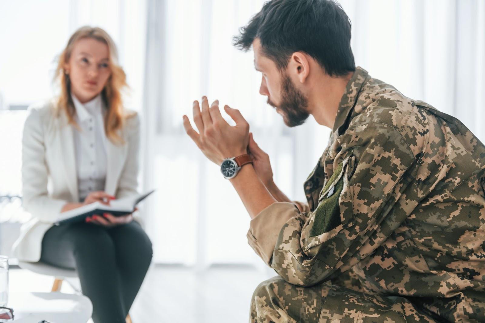 A soldier in camouflage uniform talks with a military divorce lawyer taking notes in a bright, modern office.